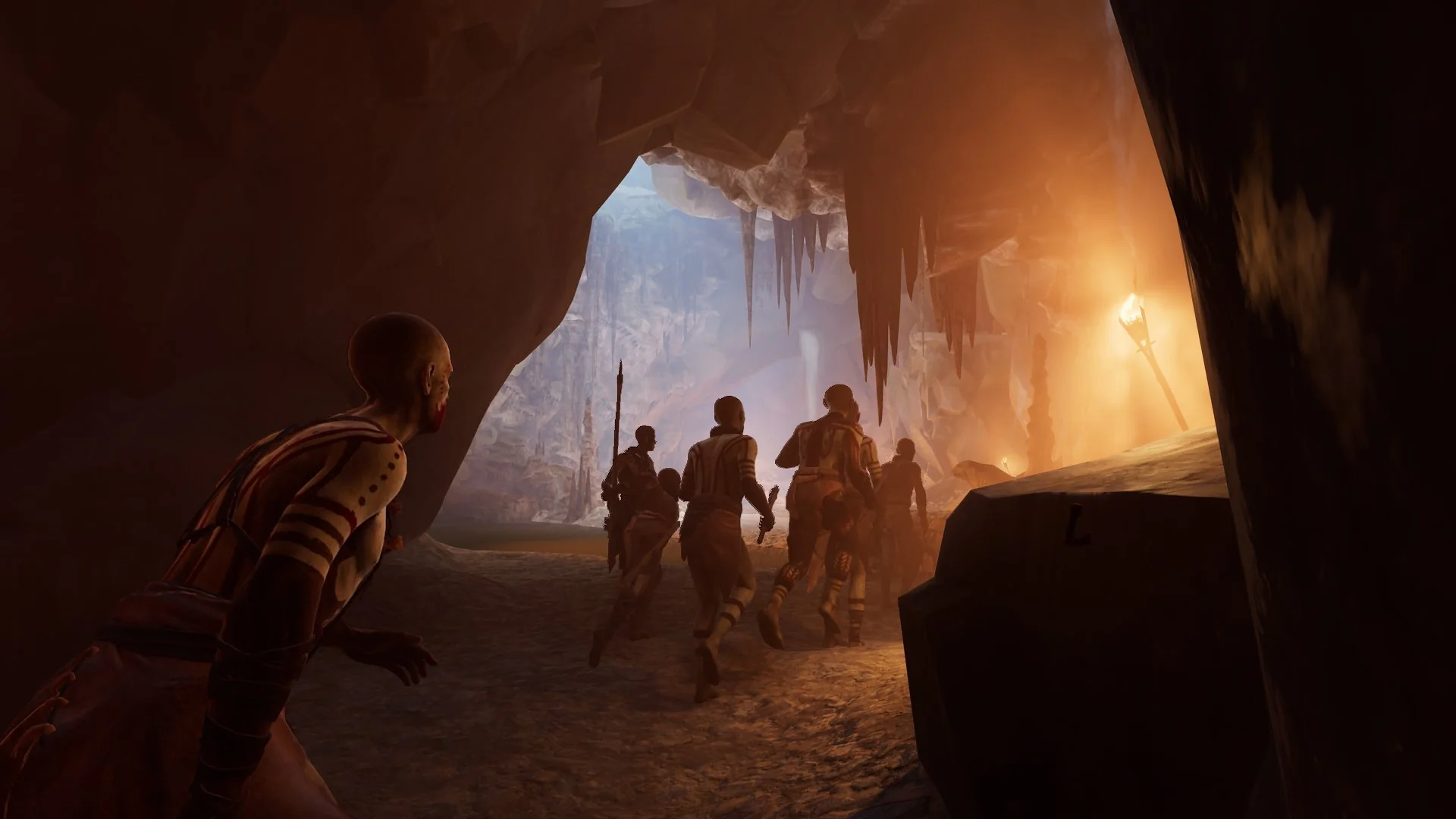 A hunting party moves through an ice-lit cave toward torchlight
